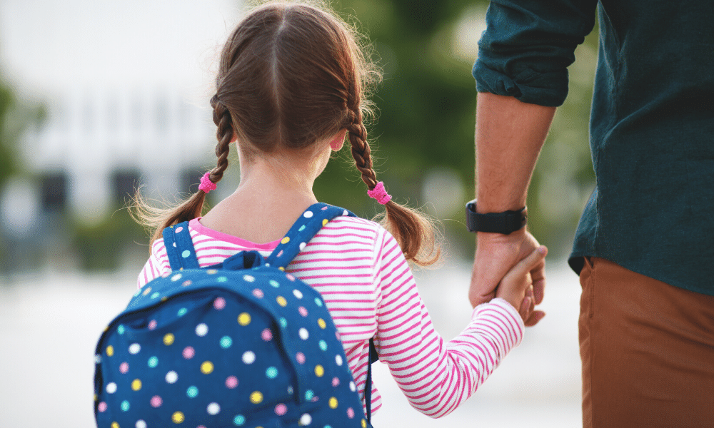 a child holding the hand of an adult as they walk