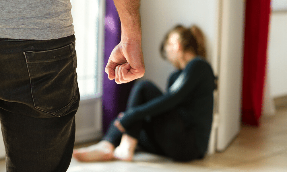 male standing with clenched fist in front of fearful woman