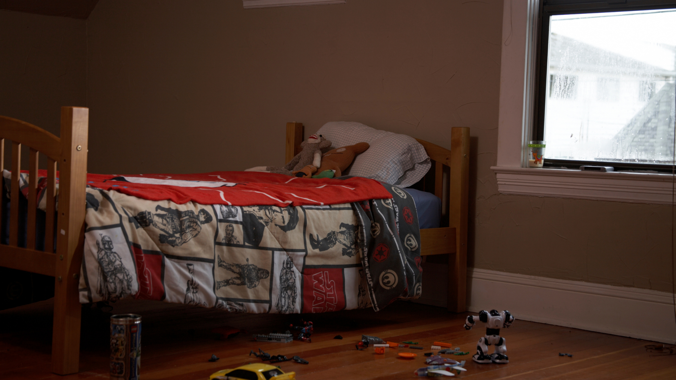 A photo of an empty child's bed with toys laying on the floor.