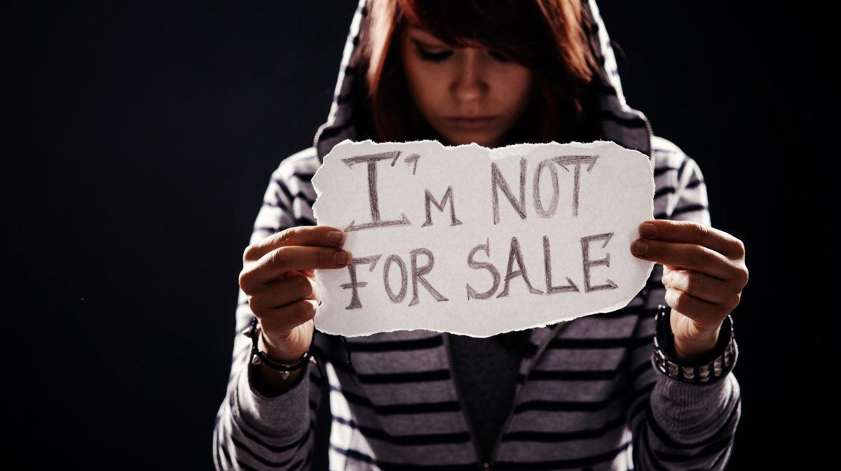 Female human trafficking victim holds sign reading I'm not for sale.