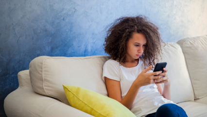 Teen texting on phone while sitting on couch